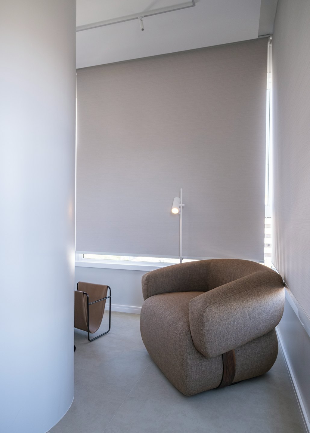 Modern brun fåtölj och lampa i ett minimalistiskt vardagsrum.