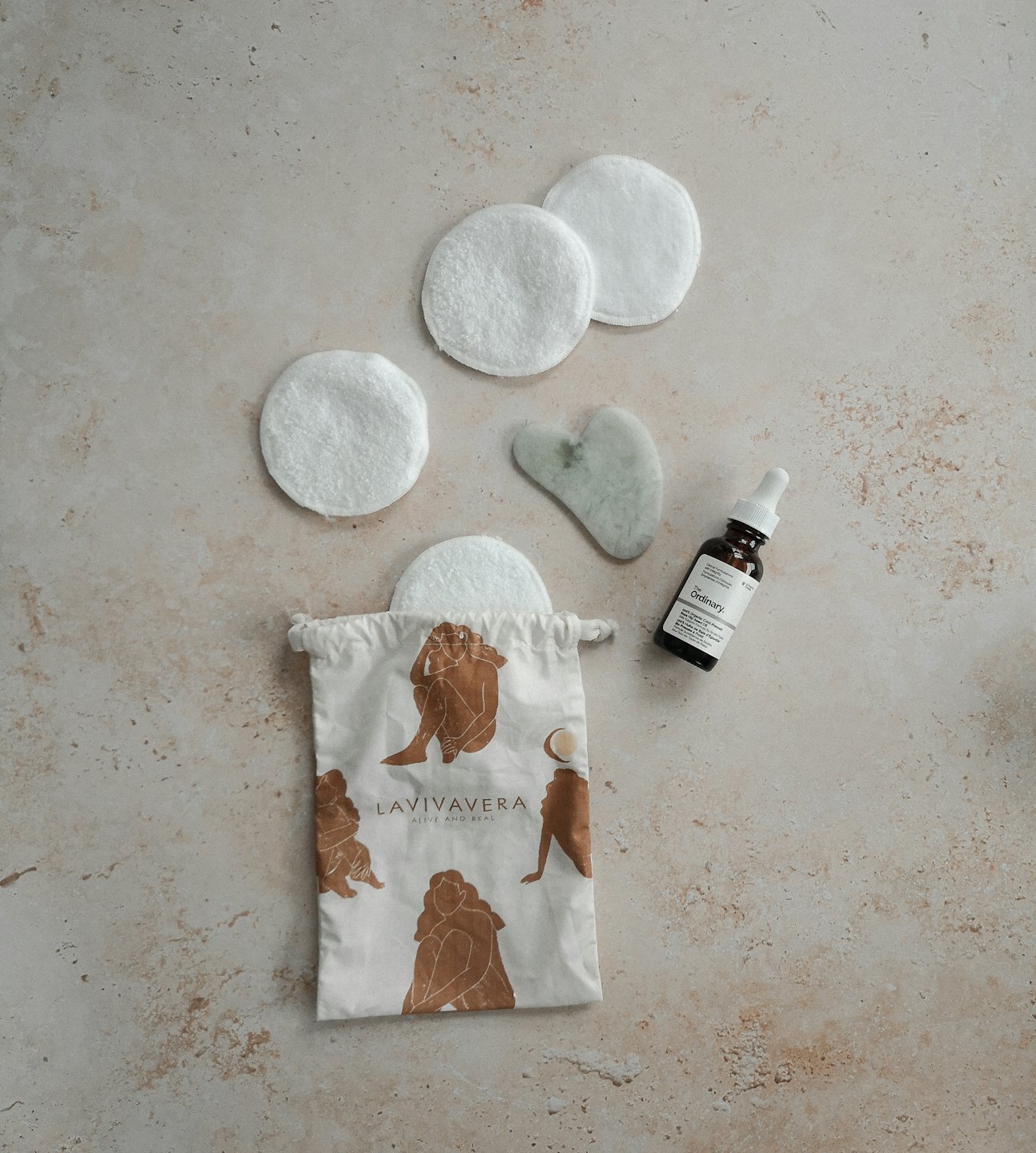 Hudvårdsprodukter med en gua sha och en serumflaska upplagda.